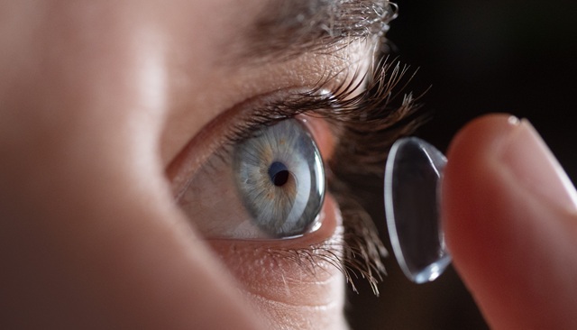 Close up of a man putting contact lenses on blue eye
